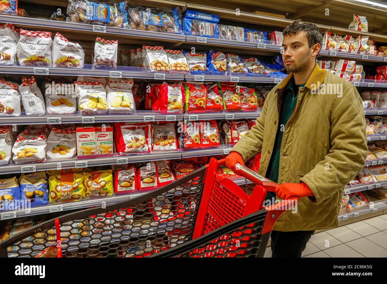 Giovane uomo che indossa guanti in un supermercato durante l'epidemia di coronavirus in Eure, Francia. Foto Stock