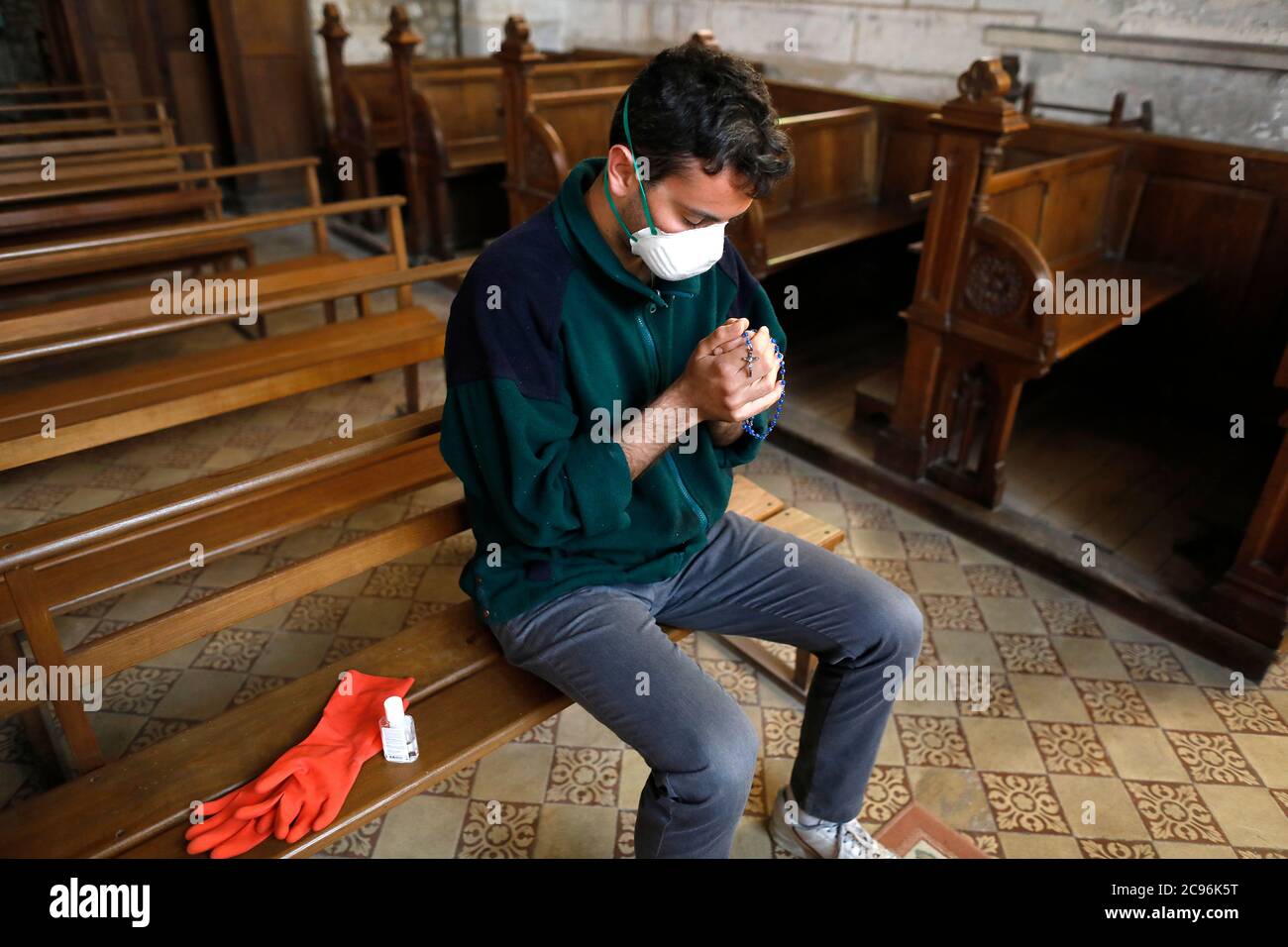 Giovane che prega nella chiesa di St Germain, Rugles, Francia durante l'epidemia di coronavirus 2020 Foto Stock