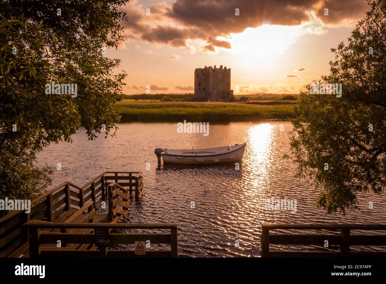 Il sole serale dietro il castello di Threave al molo sul fiume Dee, Galloway, Scozia Foto Stock