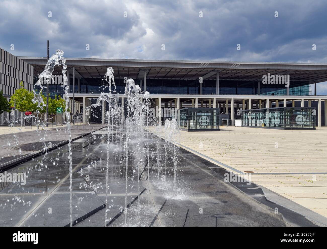 29 luglio 2020, Brandeburgo, Schönefeld: Una fontana si spruzzi di fronte al terminal dell'aeroporto di Berlino-Brandeburgo Willy Brandt (BER). Secondo l'operatore, l'apertura del Capital Airport BER è prevista per ottobre 2020. Dopo anni di ritardi, l'aeroporto inizierà a operare. La società di gestione è di proprietà degli stati di Berlino e Brandeburgo e del governo federale. Attualmente, circa 550 dipendenti e 400 volontari stanno provando la seconda fase del trasferimento operazionale e aeroportuale (ORAT). Si tratta di procedure standard per i passeggeri, dal check-in al check-in Foto Stock