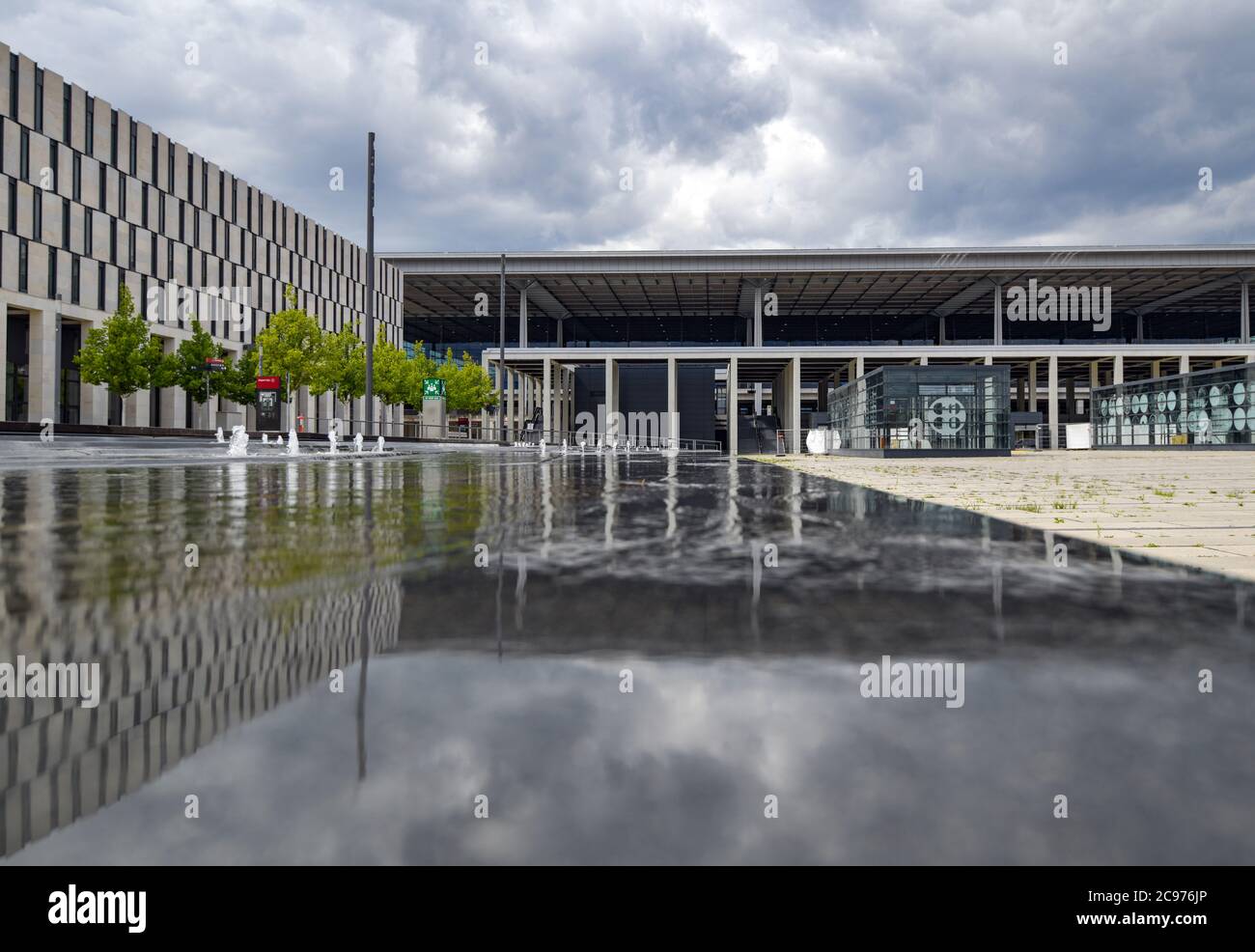 29 luglio 2020, Brandeburgo, Schönefeld: Il terminal della capitale aeroporto Berlino Brandenburg Willy Brandt (BER) si riflette nell'acqua di una fontana. Secondo l'operatore, l'apertura del Capital Airport BER è prevista per ottobre 2020. Dopo anni di ritardi, l'aeroporto inizierà a operare. I proprietari della società operativa sono gli stati di Berlino e Brandeburgo e il governo federale. Attualmente, circa 550 dipendenti e 400 volontari stanno provando la seconda fase del trasferimento operazionale e aeroportuale (ORAT). Si tratta di processi standard per passeng Foto Stock