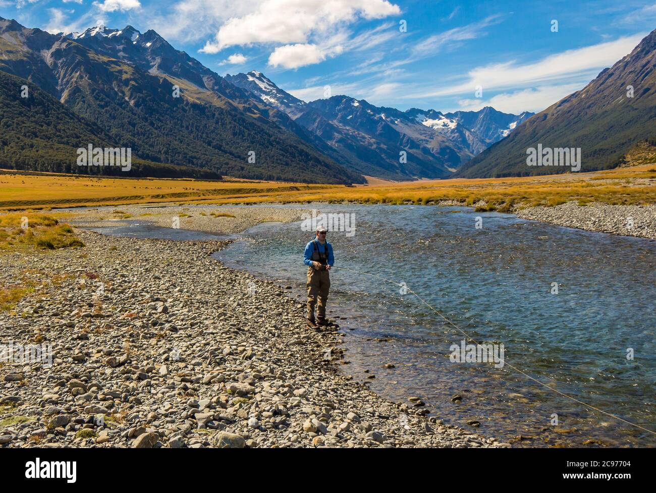 Una mosca angler pesca alla trota sul fiume Ahuriri, circondato da montagne nel bacino di MacKenzie, nell'Isola del Sud della Nuova Zelanda Foto Stock