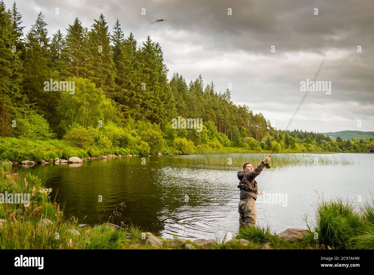 Un'azione di un pescatore di mosca che getta una mosca di luccio a Loch Stroan, Galloway Scozia Foto Stock