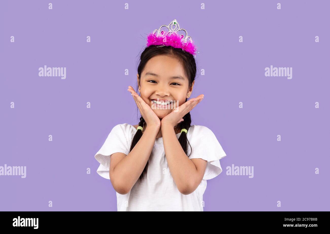 Carino ragazza asiatica che indossa la corona in posa su sfondo viola Foto Stock