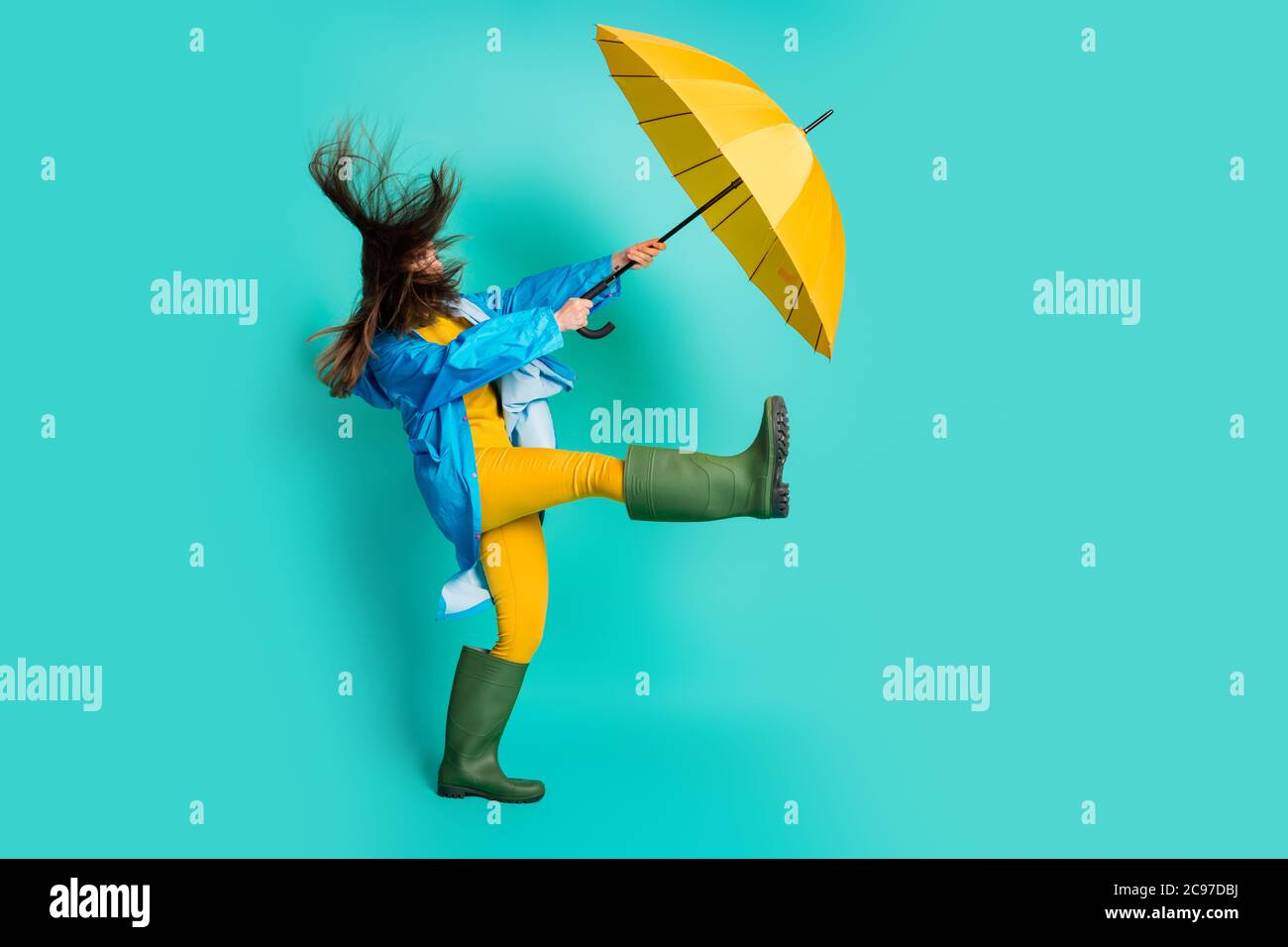 Foto profilo a lunghezza intera di signora scioccata tempesta pioggia camminare strada tenere ombrello prendere forte vento soffia via usura pantaloni felpa impermeabile Foto Stock