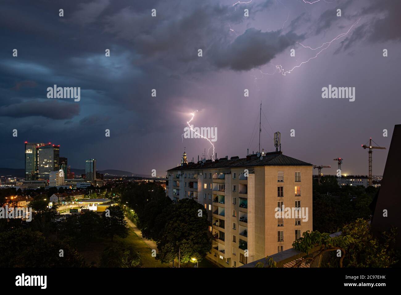 Violenta tempesta estiva con un enorme fulmine sulla città di Wienerberg a Vienna con gru di costruzione sul lato destro della foto Foto Stock