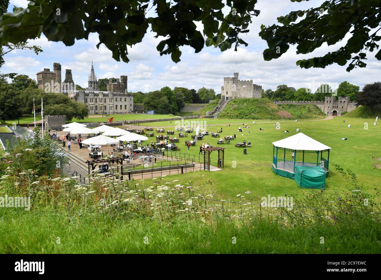 La gente apprezza il caldo al castello di Cardiff nel Galles del Sud. Foto Stock