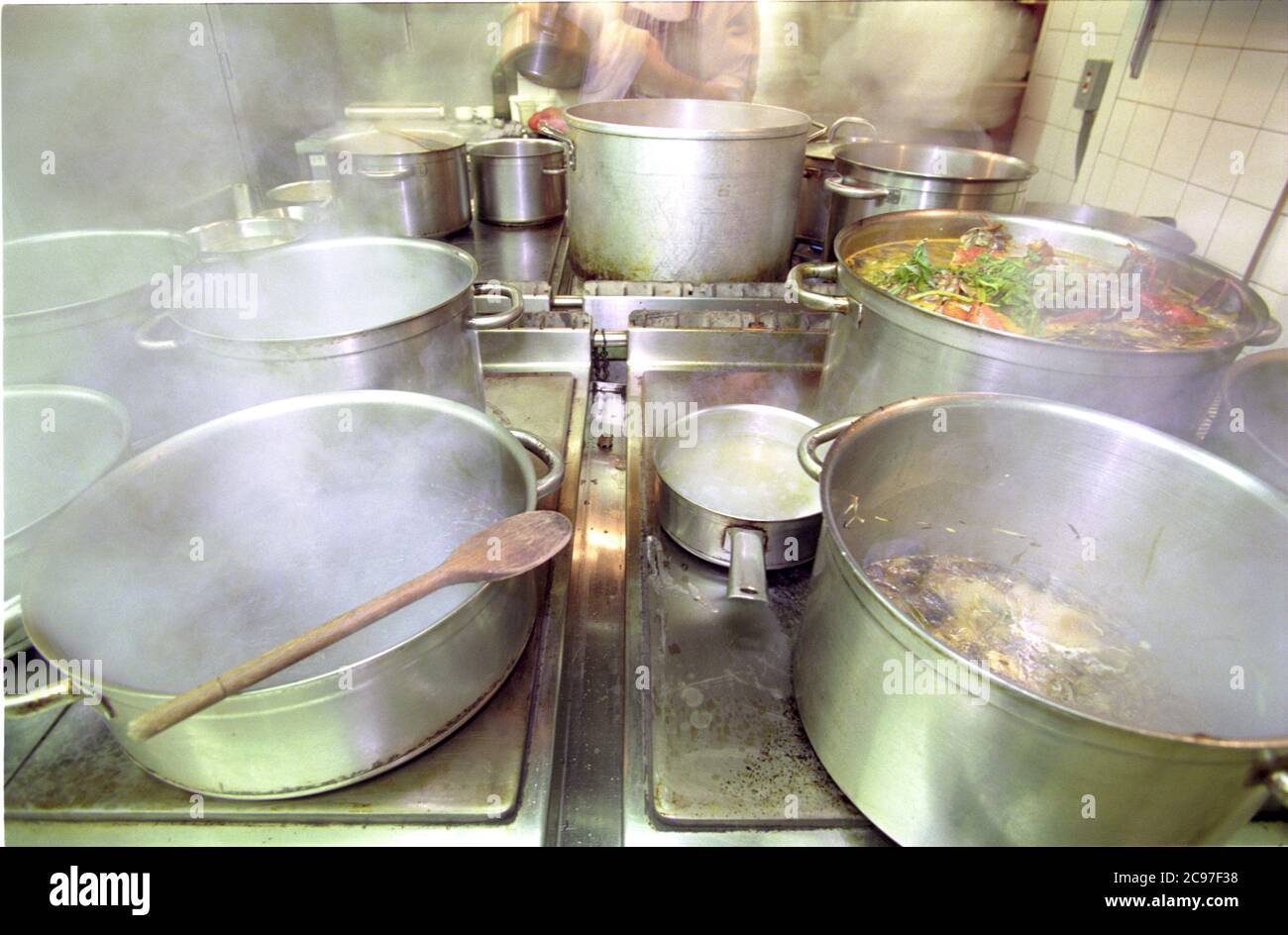 La cucina di Aubergine, Londra. Gestito dallo chef Gordon Ramsey con enormi padelle di alimenti a vapore sul piano cottura a gas. Foto Stock