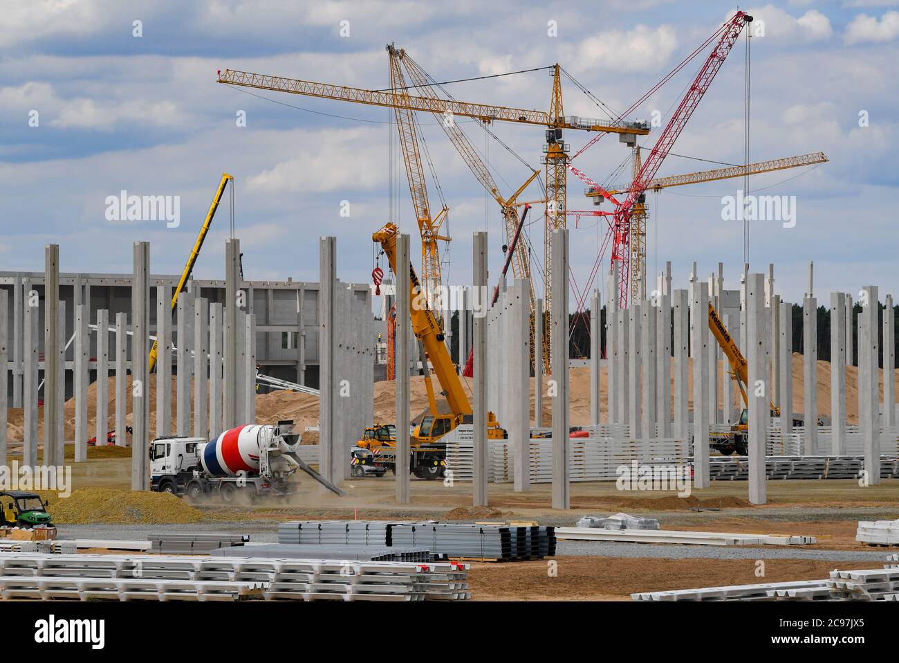 29 luglio 2020, Brandeburgo, Grünheide: Gru, macchine da costruzione e i primi pilastri in cemento per la futura fabbrica Tesla Giga sono visibili sul cantiere. A Grünheide, vicino a Berlino, un massimo di 500,000 veicoli all'anno dovranno essere dismontati dalla linea di assemblaggio a partire da luglio 2021 e, secondo i piani del costruttore, il massimo dovrebbe essere raggiunto il più rapidamente possibile. Il costruttore americano di auto elettriche si aspetta fino a 10500 dipendenti in cambio di turno per il suo primo stabilimento in Europa. Foto: Patrick Pleul/dpa-Zentralbild/ZB Foto Stock