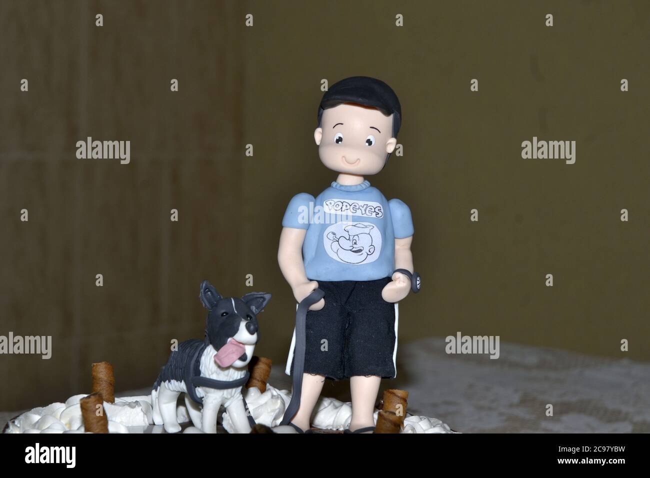 Torta di compleanno con il nastro rosso e la figura di un bambino con il suo cane in una foto zoom, su una tovaglia bianca e sfondo sfocato, Brasile, Sud America Foto Stock