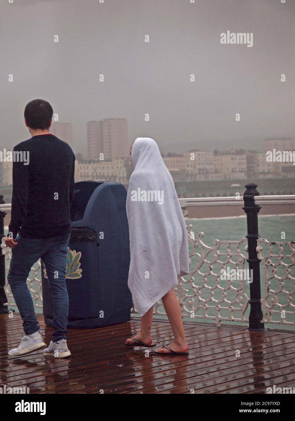 In una giornata bagnata a Brighton un bambino si avvolge in un asciugamano Foto Stock