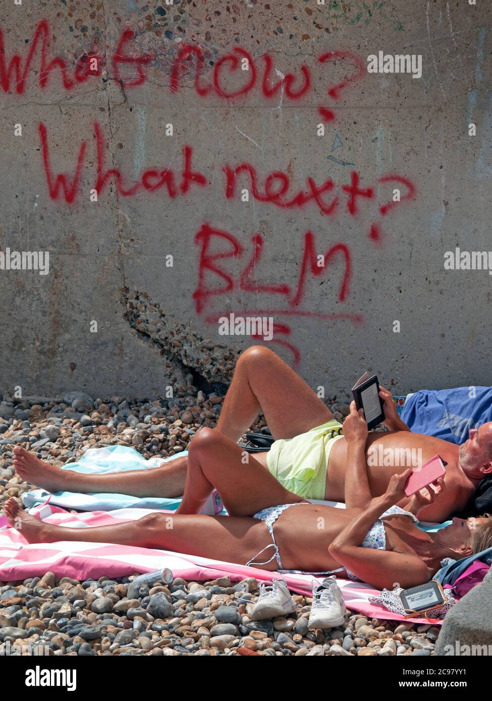 Prendere il sole sulla spiaggia di Brighton da alcuni graffiti BLM Foto Stock