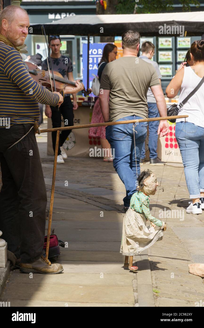 Uomo di strada che gioca la fiddle e che esegue un burattino danzante con il suo piede, York, North Yorkshire, Inghilterra, Regno Unito. Foto Stock