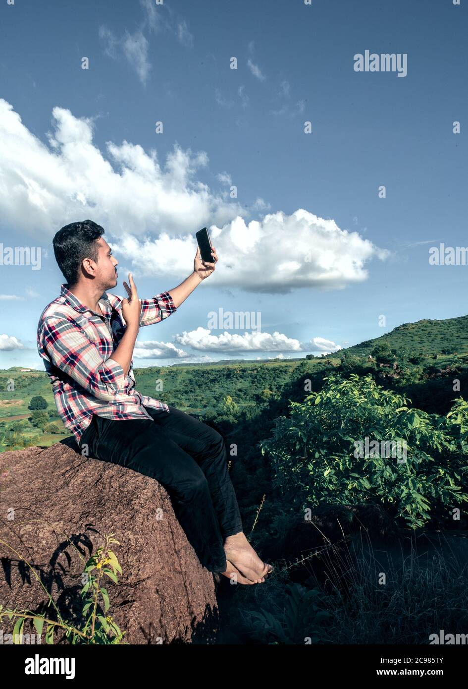 uomo seduto in cima alla collina in pietra e scattare una foto selfie durante il fine settimana con la natura verde Foto Stock