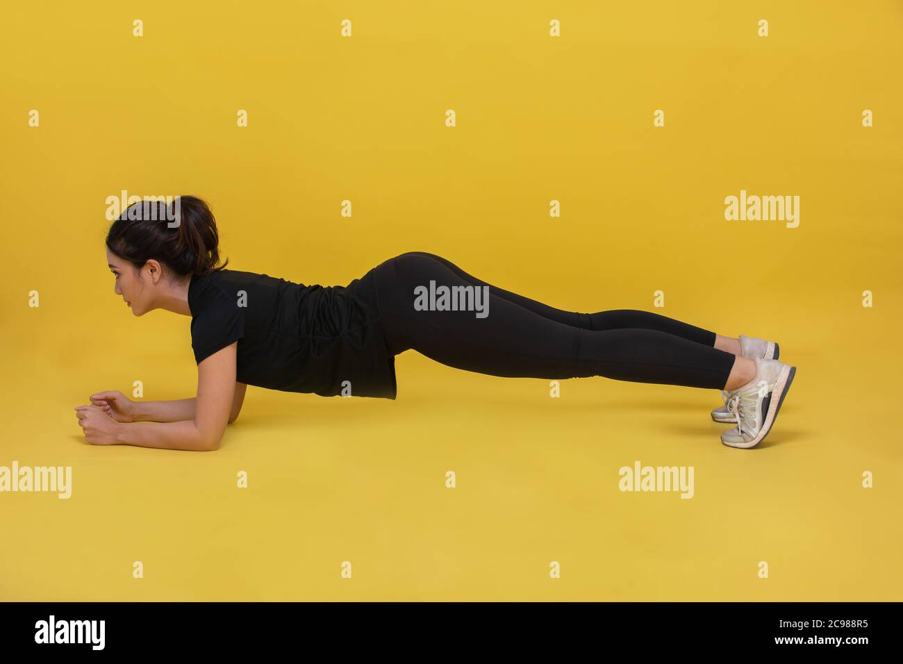 Sorriso felice bel ritratto giovane donna asiatica stretching esercizio e tavola allenamento su sfondo giallo, fitness sport ragazza aerobica e sano co Foto Stock