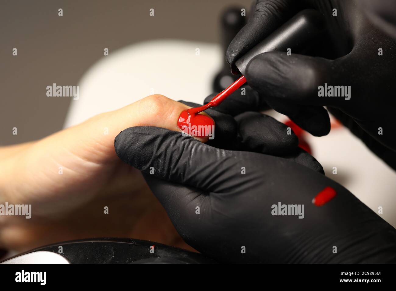 Mani in guanti neri applicare vernice rossa Foto Stock