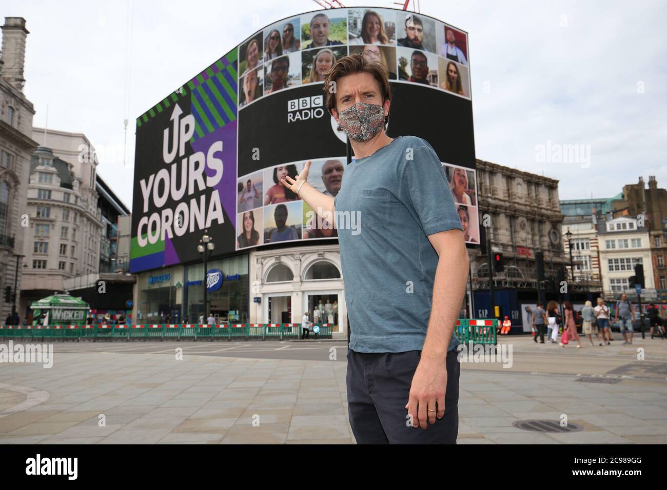 BBC radio 1 DJ Greg James a Piccadilly Circus, Londra, mentre la campagna radio 1 "Up Your Corona" viene visualizzata sullo schermo Piccadilly Lights. Il display di 10 minuti è caratterizzato da una persona di ogni paese del mondo. Foto Stock
