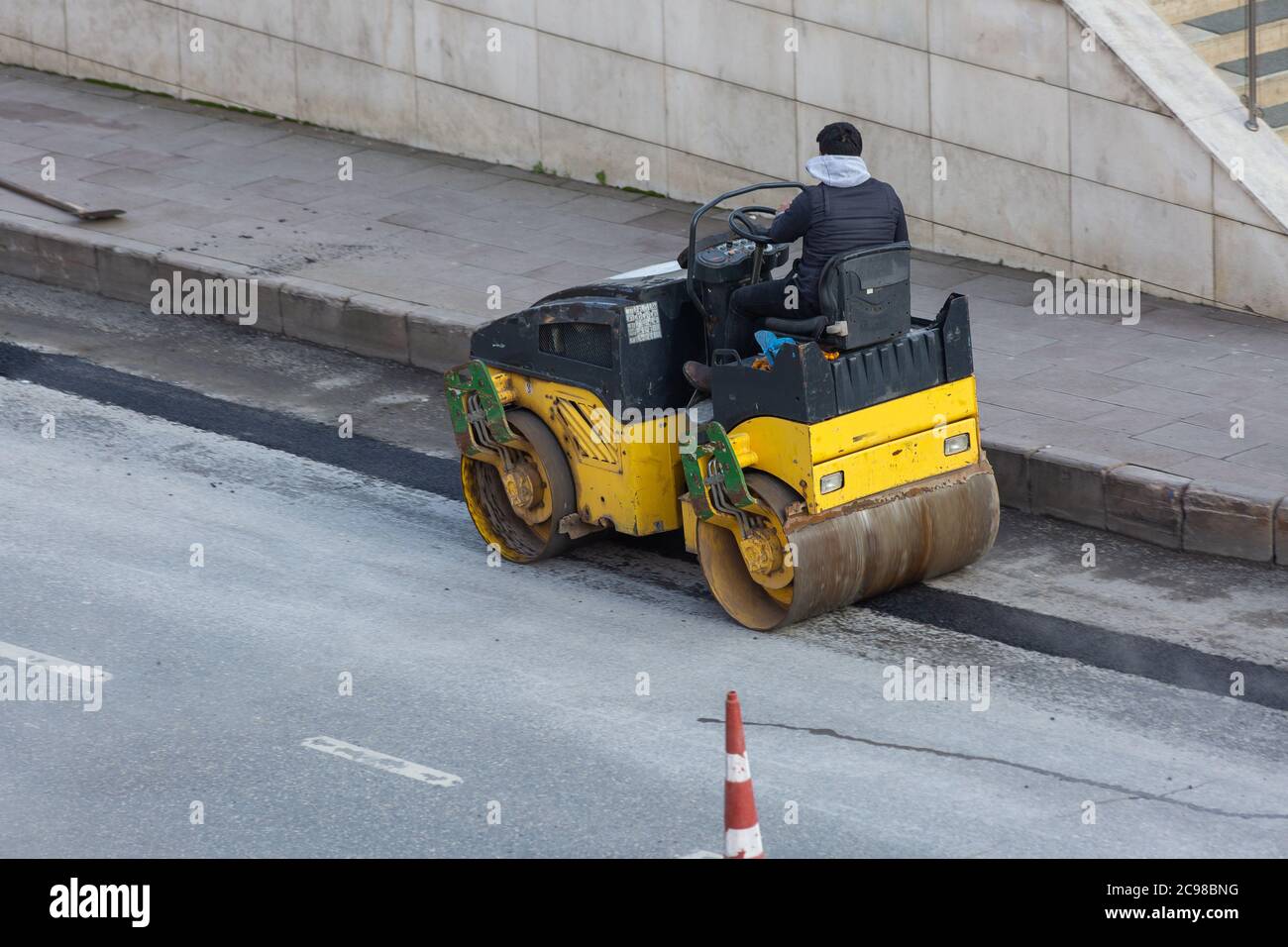 Operaio della costruzione stradale, patching strada asfaltata con compattatore a rulli e appiattimento della nuova asfalto a Istanbul, Turchia. Foto Stock