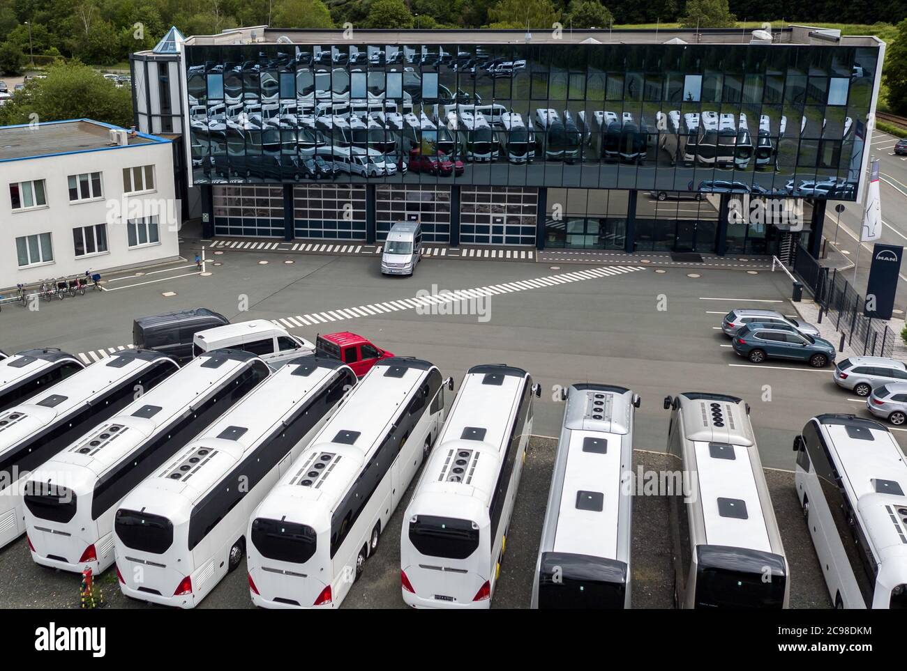 16 luglio 2020, Sassonia, Plauen: Parcheggio per pullman e furgoni di fronte al MAN Bus Modification Centre (BMC). MAN, il modificatore di autobus basato su Plauen, guarda positivamente ai prossimi mesi dopo un crollo delle vendite durante la crisi della corona e la minaccia di tagli di posti di lavoro in azienda. Grazie all'attenzione alla mobilità elettrica e ai desideri individuali dei clienti, la posizione è ben posizionata per il futuro. (Girato con un drone) Foto: Jan Woitas/dpa-Zentralbild/ZB Foto Stock