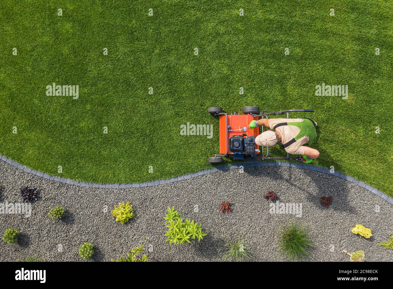 Potente aeratore per prati a benzina per il controllo della paglia di prato e la riduzione della compattazione del terreno. Manutenzione sul campo dell'erba del cortile. Giardiniere caucasico in Foto Stock
