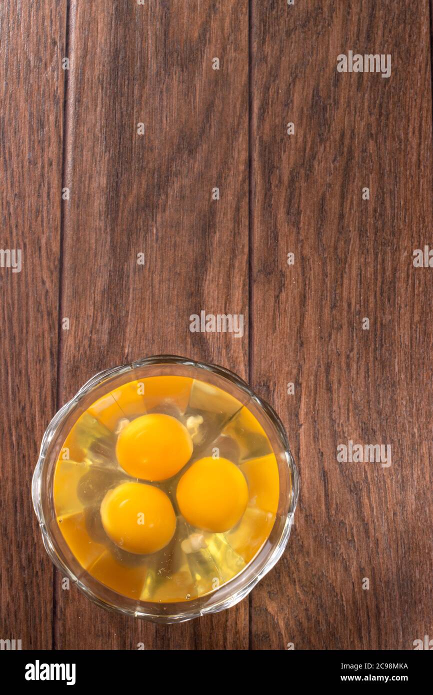 Tre uova grezze in un recipiente di vetro. Il contenuto di uova di pollo per cucinare uova e altri piatti. Foto Stock