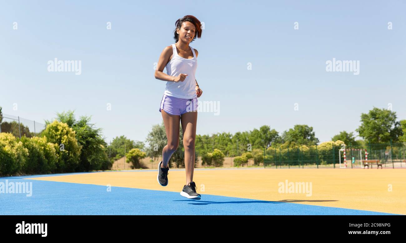 Bruna donna che corre entusiasta in pista. Spazio per il testo. Concetto di vita sana. Foto Stock