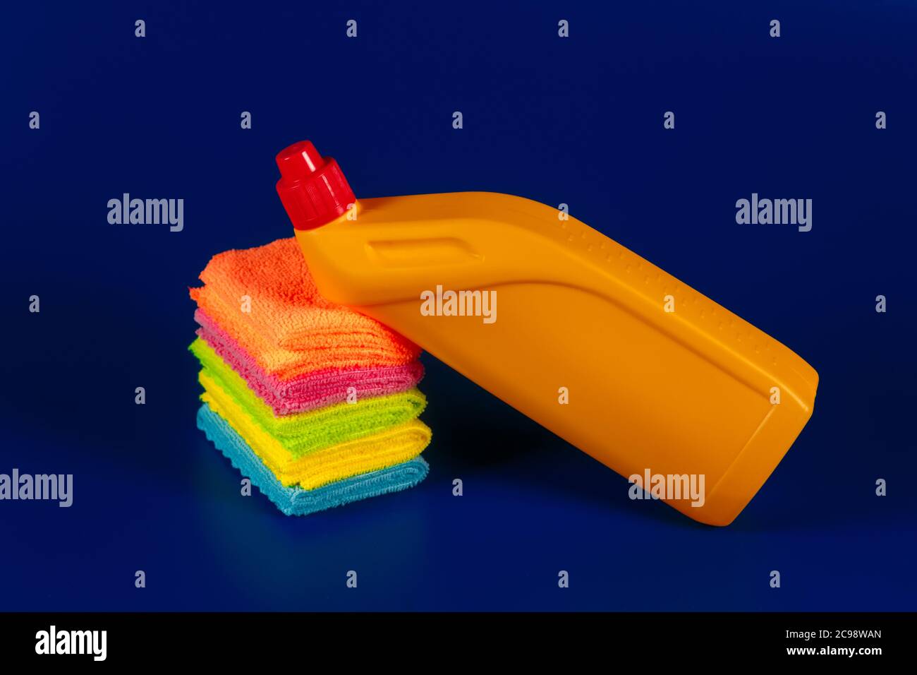 detergente giallo e stracci su sfondo blu. Foto Stock