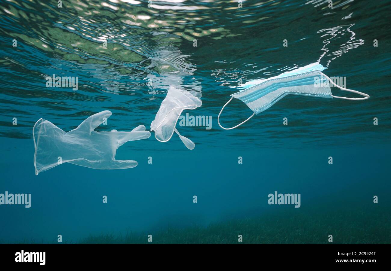 Inquinamento da rifiuti di plastica in mare da coronavirus COVID-19 pandemic, guanti con una maschera facciale che galleggia sotto la superficie dell'acqua Foto Stock
