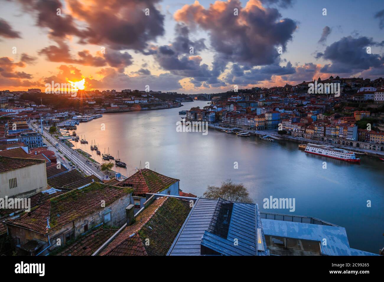 Tramonto sui tetti della città di Porto. Fiume Douro nella città costiera portoghese. Nuvole e raggi di sole la sera. Vista sulla città dalla collina Foto Stock