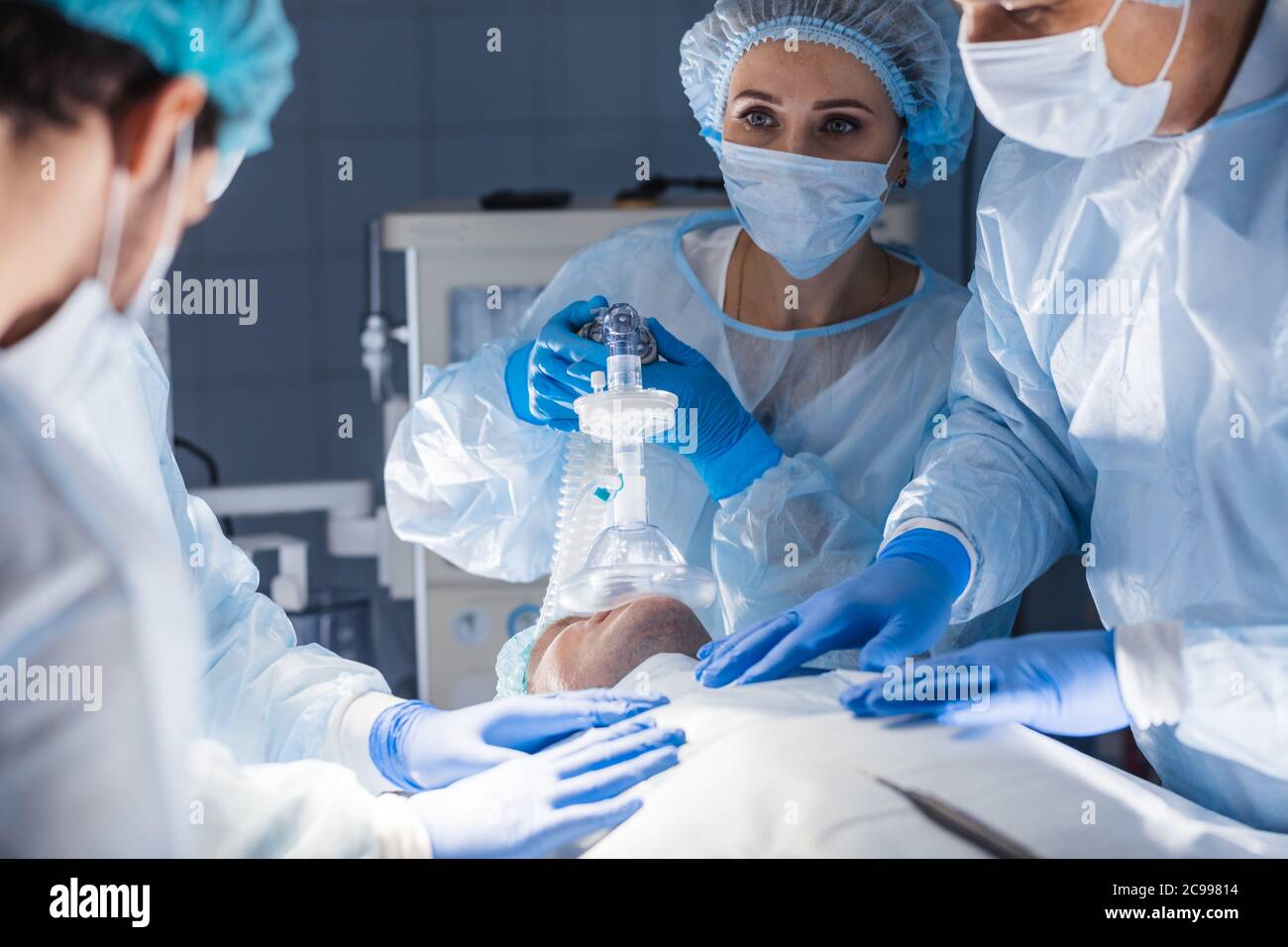 Infermieri femminile mettendo le maschere di ossigeno sul paziente in sala operatoria. Pre-ossigenazione per anestesia generale. Strumenti chirurgici Foto Stock