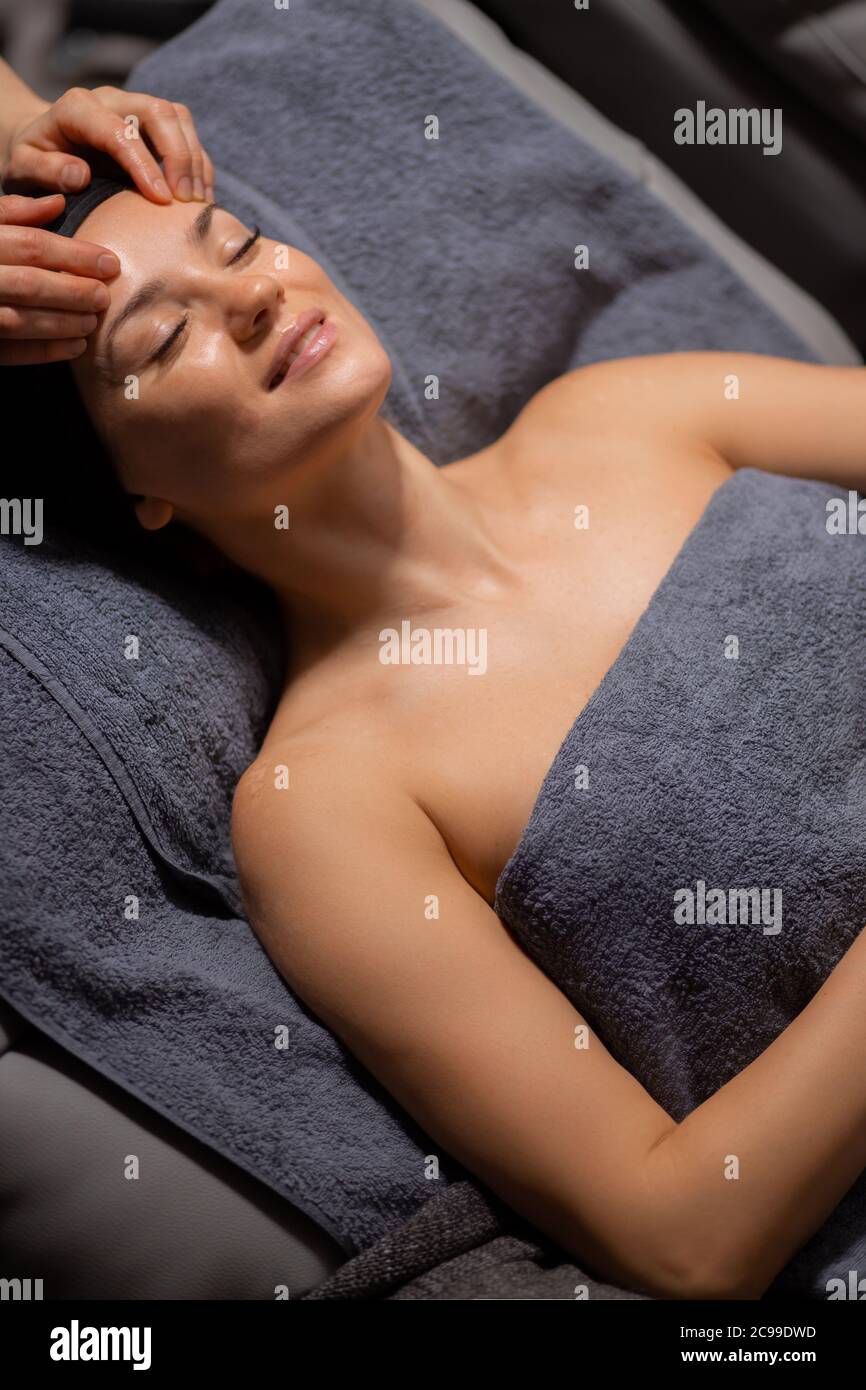 donna giovane e bella sdraiati sul banco massaggi, rilassati e goditi, ottieni un trattamento sano della pelle, nel lussuoso centro benessere Foto Stock