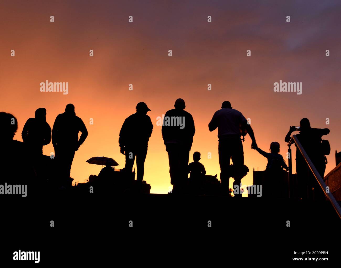 sagome di persone contro il cielo serale Foto Stock