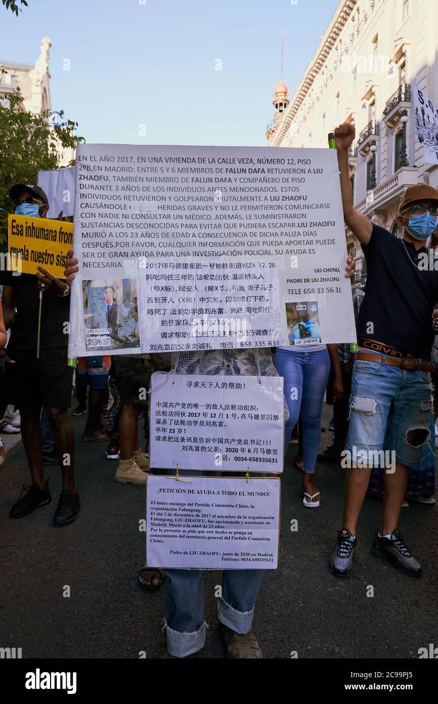Un manifestante porta fogli stampati di testo spagnolo e cinese montati su una tavola di cartelli durante la marcia "Papers for everyone", Madrid, 19 luglio 2020 Foto Stock