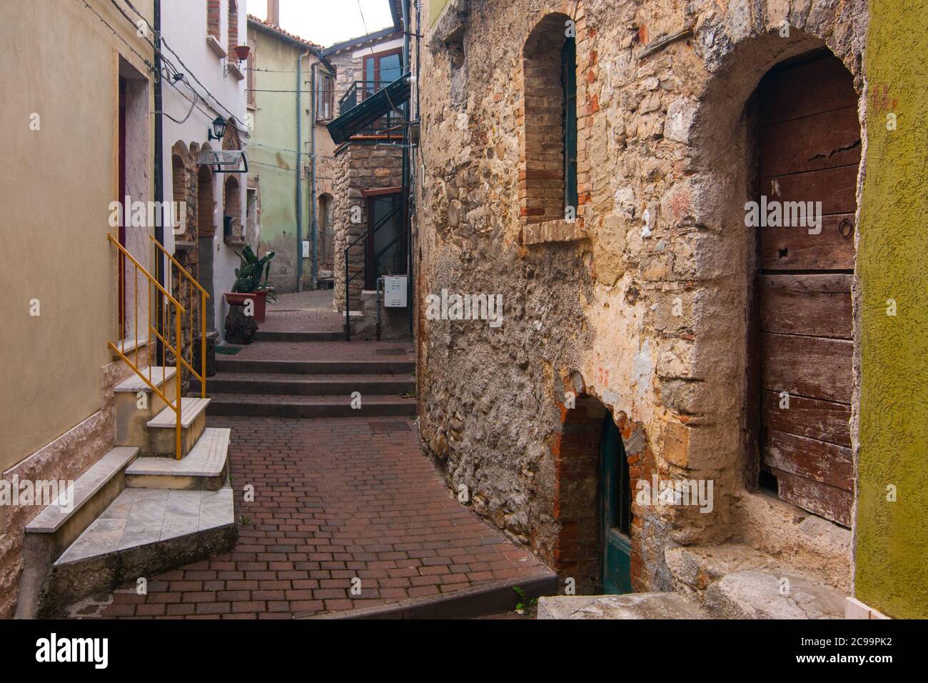 Una tipica strada storica nel villaggio italiano di Torella Di Sannio in Molise con edifici in mattoni e uno scooter Foto Stock