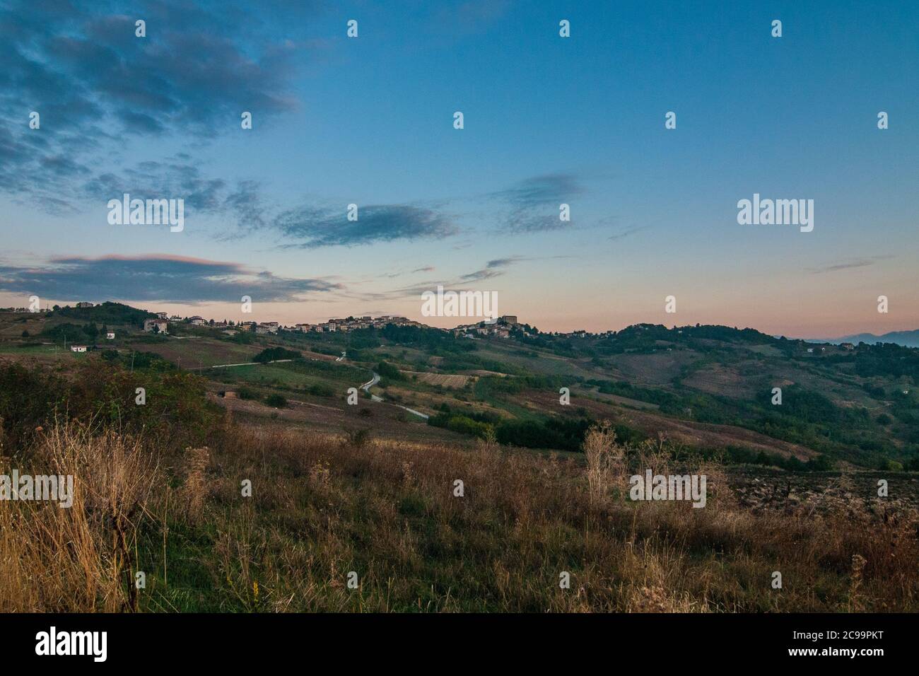 Tipico paesaggio collinare italiano all'alba, con verdi colline e un cielo blu, rosa e giallo Foto Stock