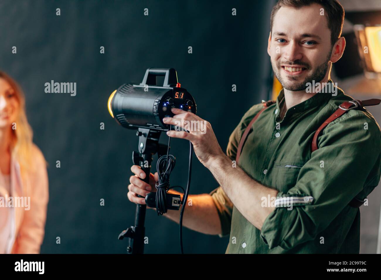 felice piacevole fotografo in piedi vicino al flash attrezzature e in posa per la fotocamera, passatempo preferito Foto Stock