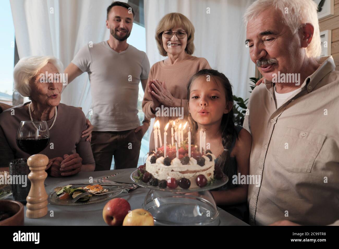 Grande famiglia felice che festeggia il compleanno del loro padre con torta di compleanno al tavolo a casa Foto Stock