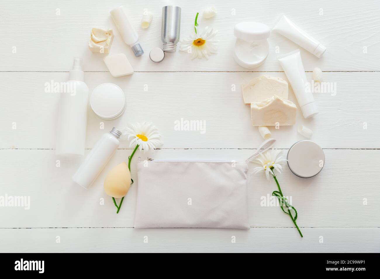 Impostare i prodotti per la cura della pelle naturale in confezioni bianche su un tavolo di legno. Cosmetici termali per la salute di bellezza a casa. Borsa cosmetica, prodotti da bagno, fiori, sapone Foto Stock