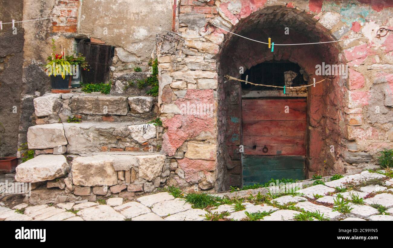 Una strada tipica dell'antico borgo di Torella del Sannio in Molise, con alcuni scalini, un vaso di fiori e una porta verde e marrone Foto Stock