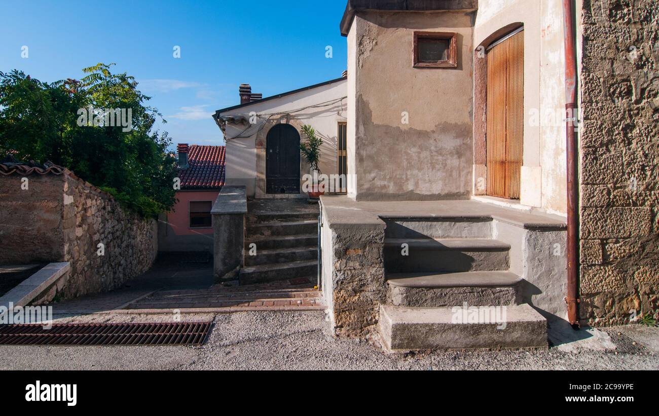 Particolare di alcune case antiche e di alcuni alberi verdi in Una strada tipica dell'antico borgo di Torella del Sannio in Molise Foto Stock