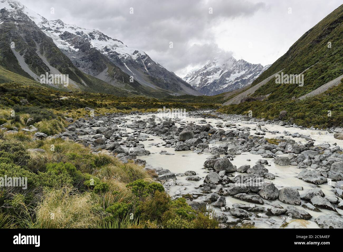 Percorso escursionistico Hooker Valley Track, Nuova Zelanda. Fiume che conduce al lago Hooker con ghiacciaio sopra la vista del Parco Nazionale Aoraki Mount Cook con neve coperta Foto Stock