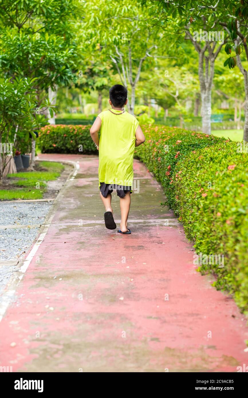 Vista rara del giovane ragazzo asiatico che corre in giardino. Foto Stock