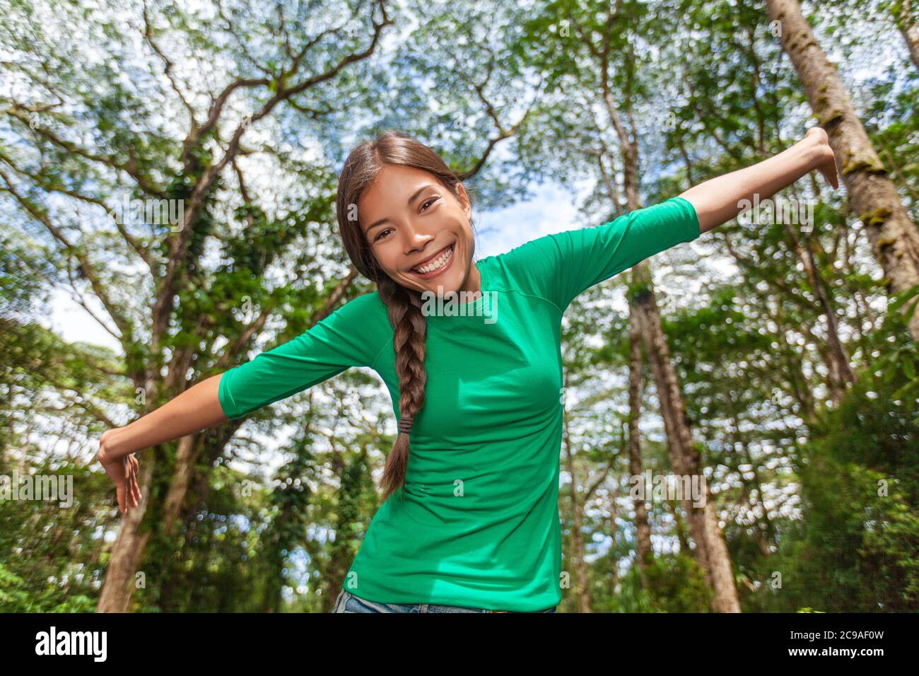 Ambiente amichevole ragazza felice godendo natura foresta all'aperto in sfondo naturale soleggiato. Donna asiatica a braccia aperte in libertà divertendosi in fresco Foto Stock