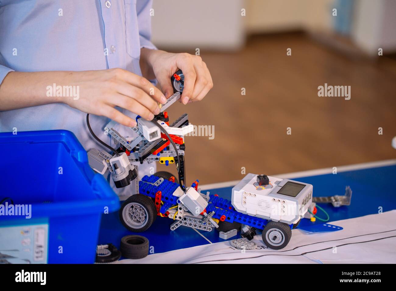 Primo piano delle mani dei ragazzi durante la creazione di un robot in laboratorio, lezioni di robotica. Sviluppo precoce, fai da te, innovazione, concetto di tecnologia moderna Foto Stock