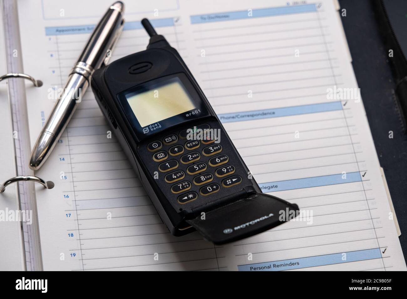 Telefono cellulare degli anni novanta e una penna fontana d'argento che si trova sopra un diario di grande formato. Foto Stock