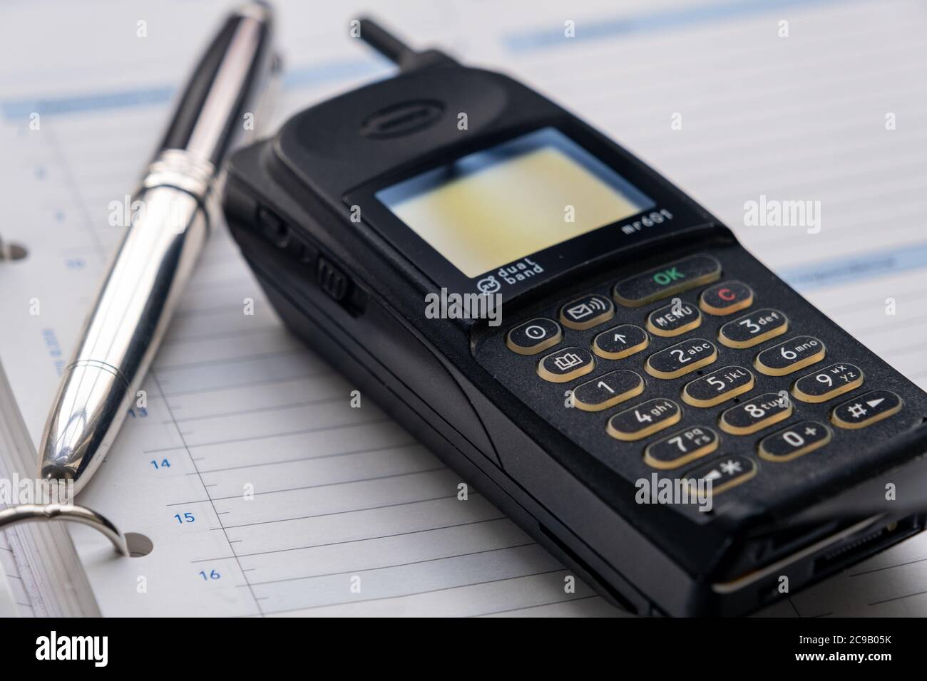 Telefono cellulare degli anni novanta e una penna fontana d'argento che si trova sopra un diario di grande formato. Foto Stock
