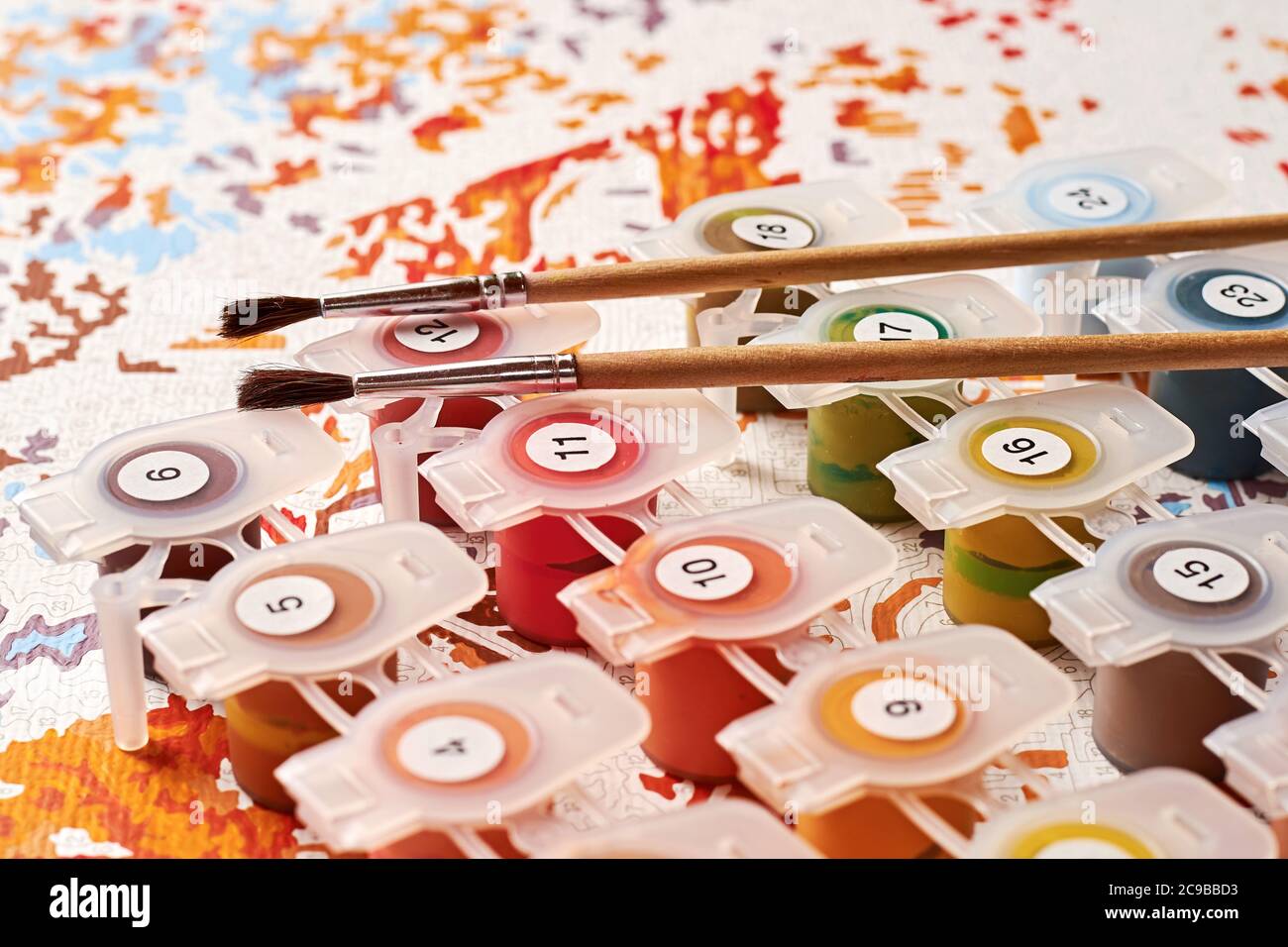 Colori vivaci e pennelli sono disposti su tela con numeri preparati per l'educazione artistica. Hobby e attività di svago. Texture di sfondo e lezioni d'arte Foto Stock