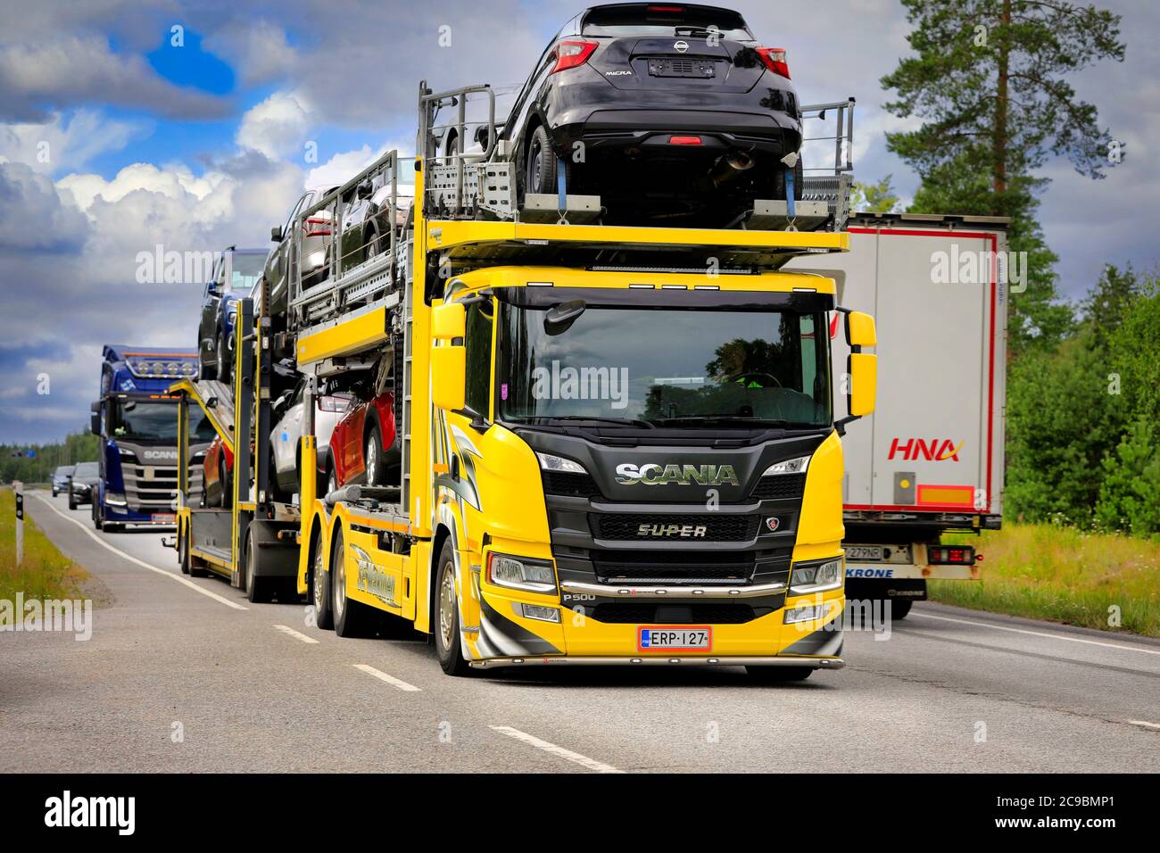 Il vettore auto Scania P500 personalizzato giallo se Mäkinen trasporta nuove auto nel traffico pesante dell'autostrada 25. Raasepori, Finlandia. 24 luglio 2020. Foto Stock