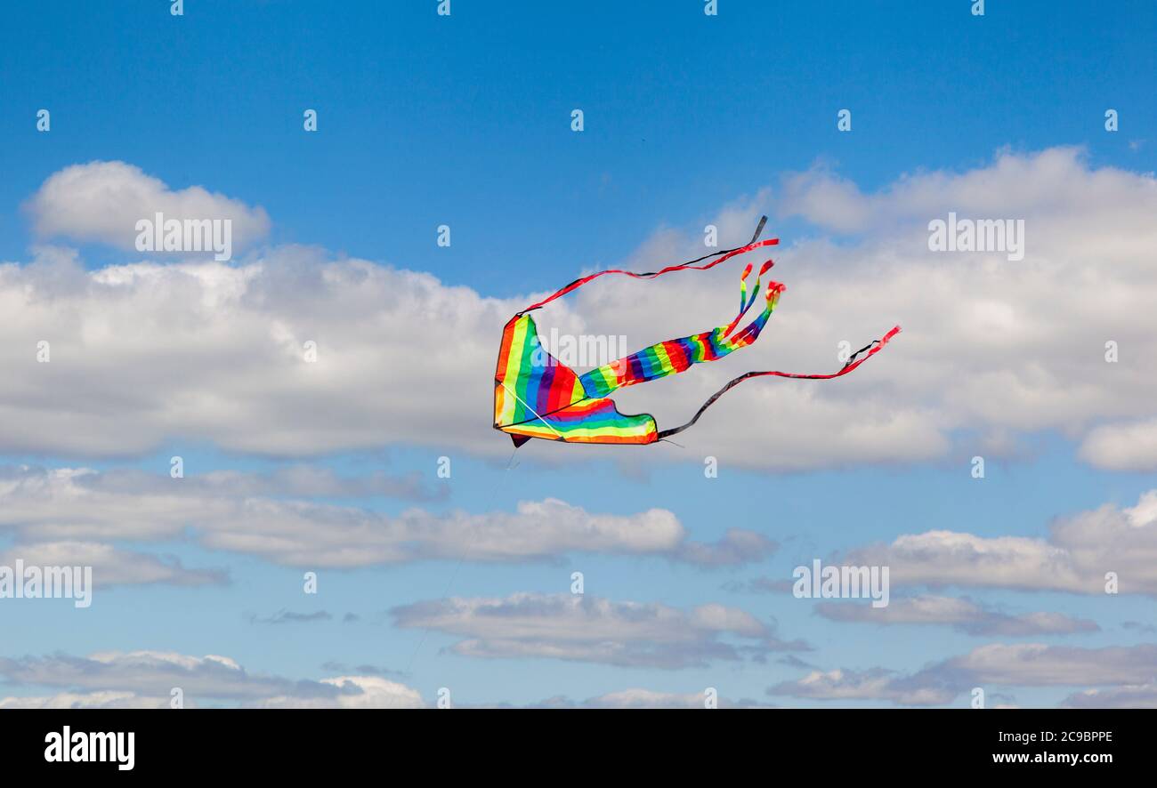 Aquilone dai colori vivaci che volano in un cielo soleggiato Foto Stock