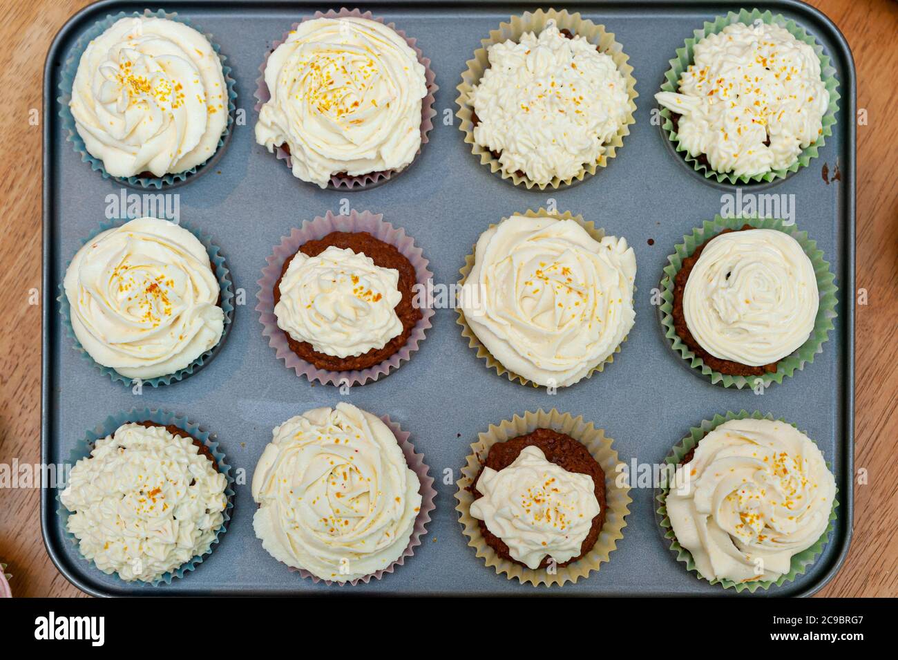 Cupcakes cotto in casa splendidamente decorato con crema di burro sulla parte superiore posto in teglia da forno. Foto Stock